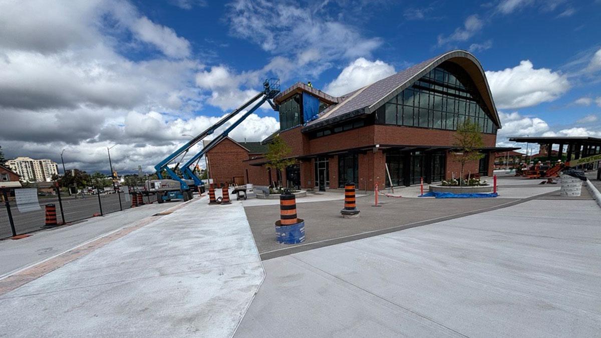 Exterior view of the Barrie Allandale Transit under construction, featuring its distinctive arched roof, with construction work and machinery visible.
