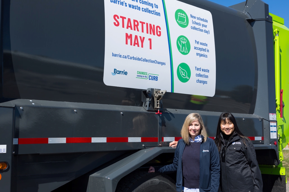 Stephanie Mack, City of Barrie Associate Director of Waste Management and Environmental Sustainability and Paulina Leung, Chief Sustainability Officer at Emterra Environmental standing with waste collection truck displaying changes coming May 1