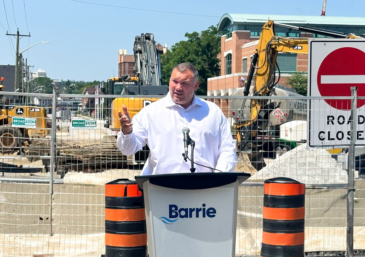 Mayor Alex Nuttall speaks at the podium in front of a road construction site