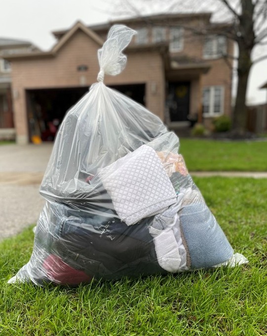 Clear bag filled with textiles placed at the curb