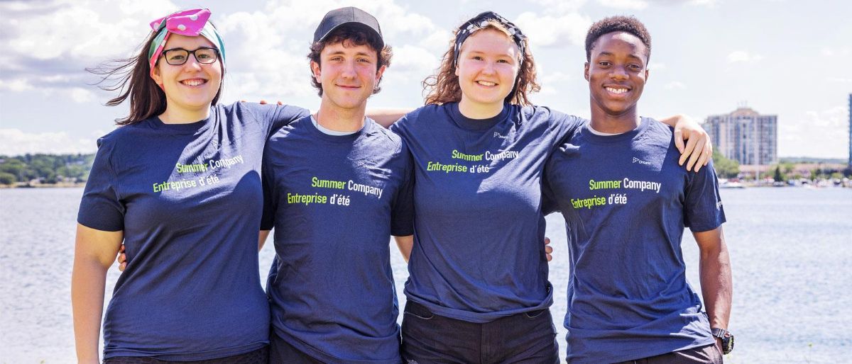 Group of smiling students wearing Summer Company t-shirts at the Barrie waterfront. 