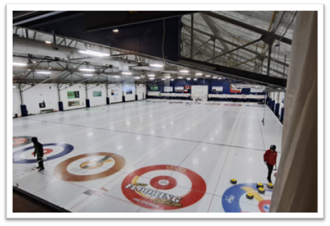 Curling rink with people, stones, and colorful target circles.