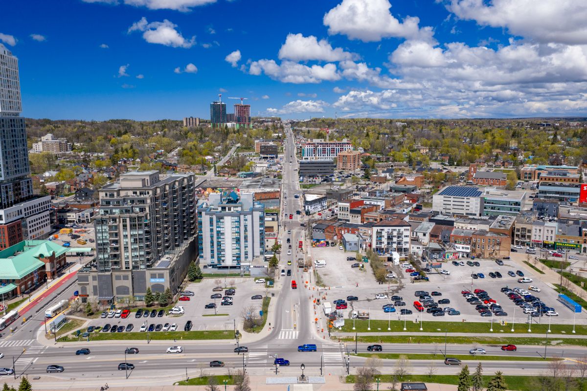 Aerial view of a vibrant cityscape with buildings, green trees, and a road under construction.
