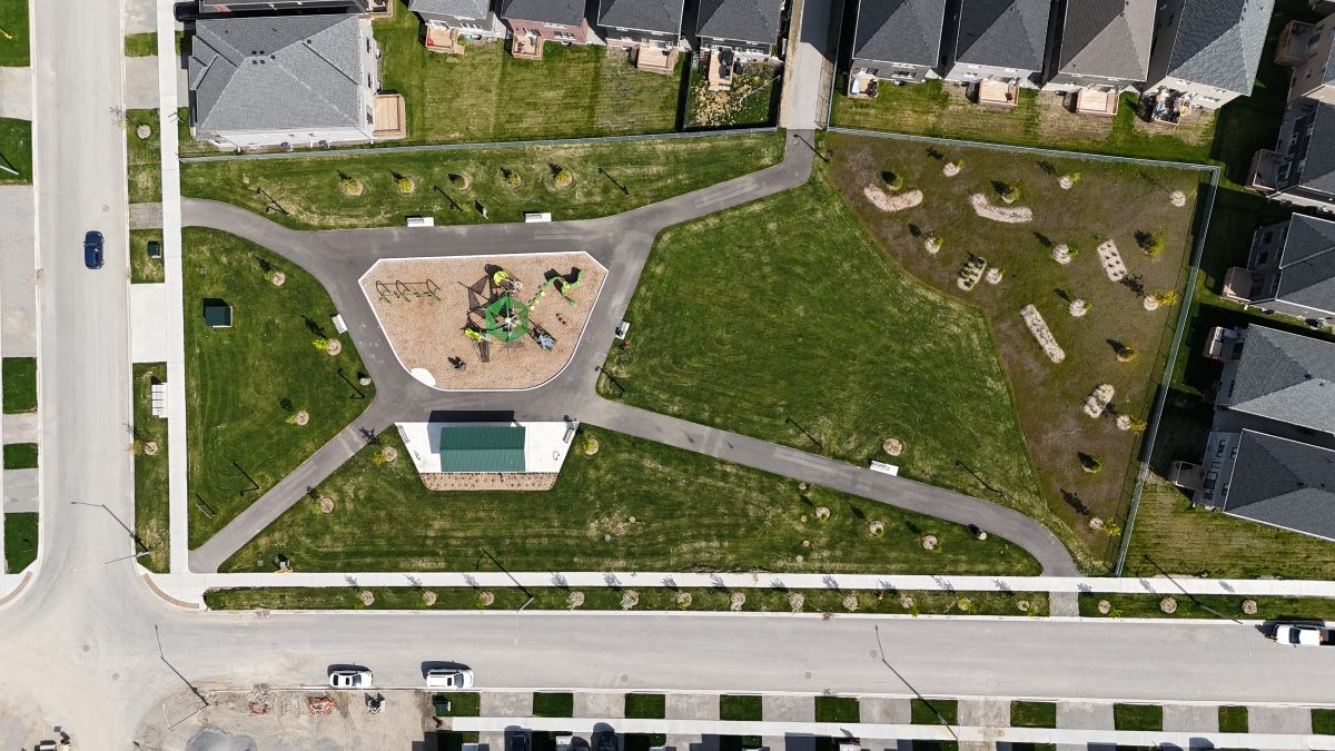 Aerial view of a park with a playground, pathways, and surrounding residential homes.