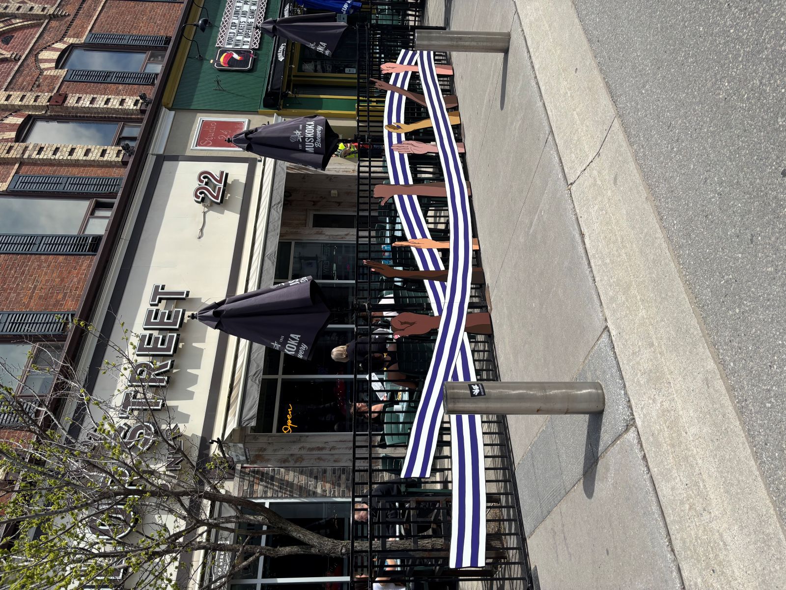 Restaurant with artwork on the patio fence of a white and purple belt runs and hands of different skin tones doing sign language.