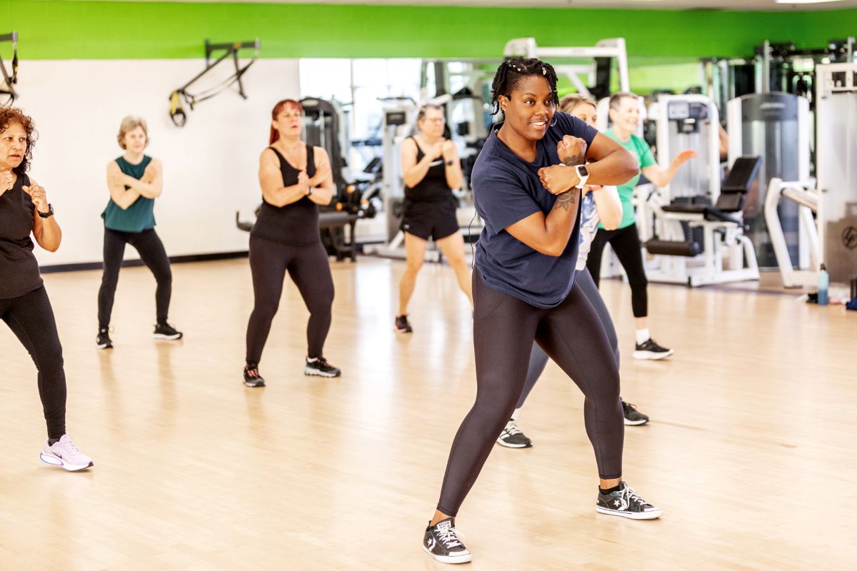 A group of people exercising in a fitness studio, led by an instructor.
