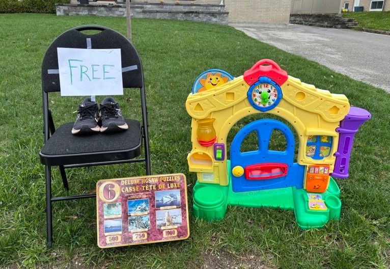 Black chair with a sign reading "FREE," shoes, and a colourful playhouse on grass.