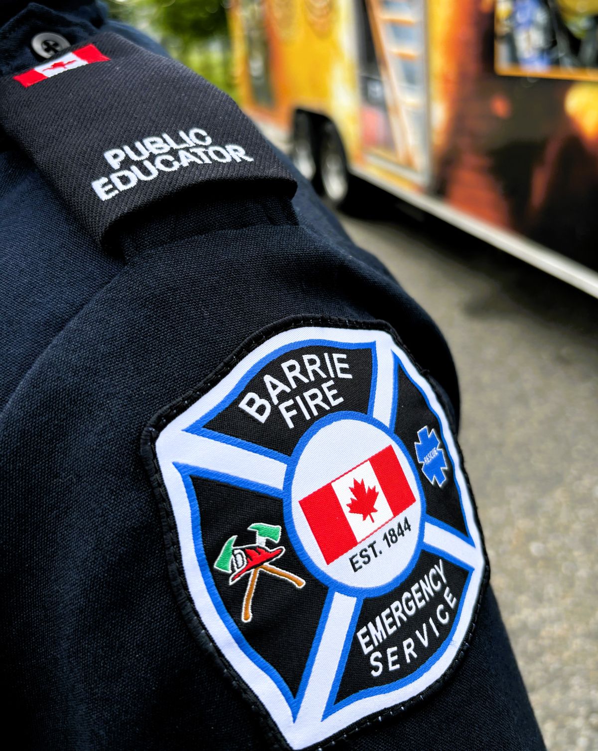 Close-up of a shoulder patch featuring "Barrie Fire Emergency Service" logo and "Public Educator" text.