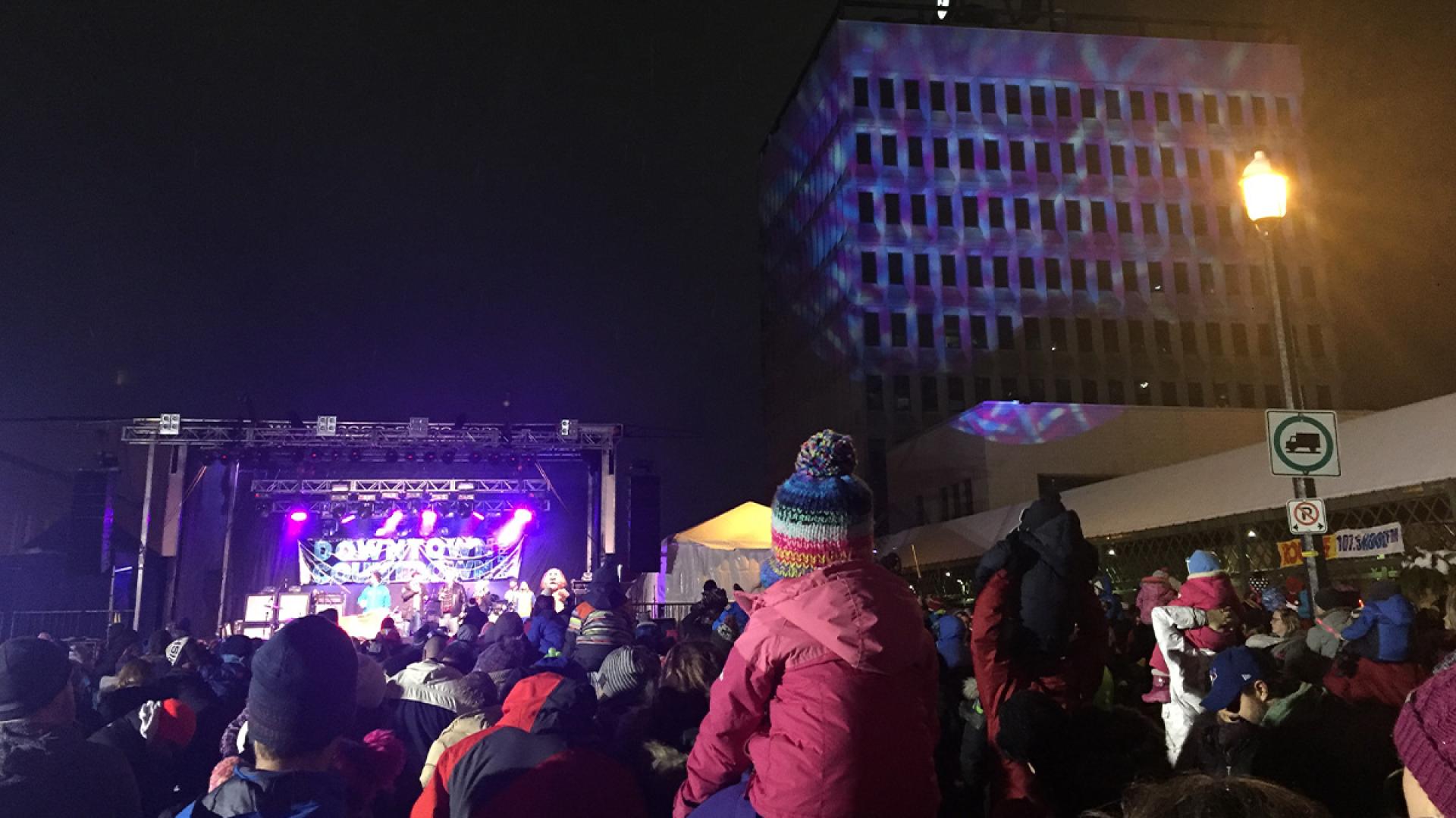 crowd watching concert at night with Barrie City Hall in background