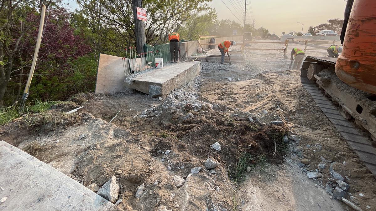 Workers removing sidewalk, parapet, and wingwall