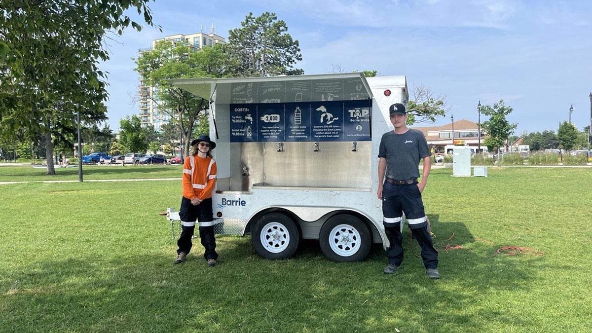2 staff people standing in front of water trailer