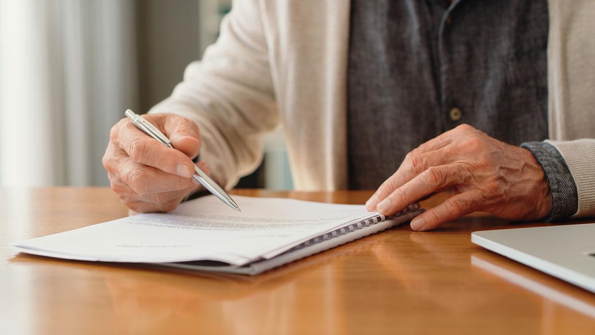 Hands holding pen, signing paper