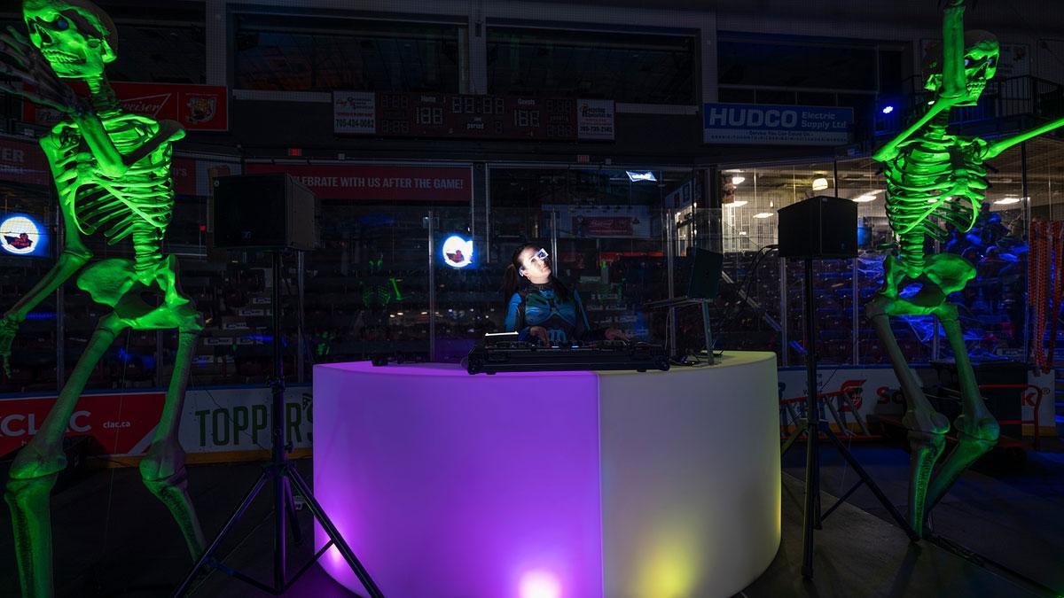 Skeleton statues glowing in green light around DJ booth
