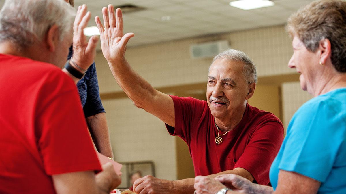 Seniors playing cards and high-fiving