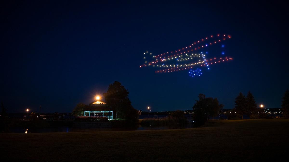 Colourful drone lights forming the shape of a bi-plane in the night sky