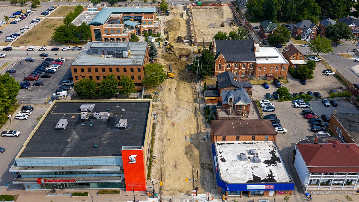 Aerial view of a construction site near well-known buildings including Scotiabank and BMO. The area features several other commercial buildings, parking lots, and some greenery.