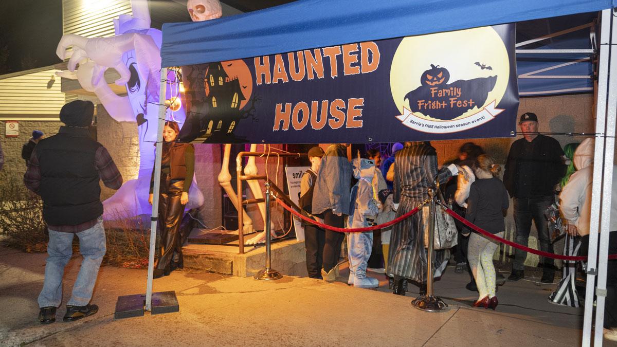 Visitors lining up at the entrance of a 'Haunted House' at the Family Fright Fest event, decorated with Halloween-themed inflatables and lights.