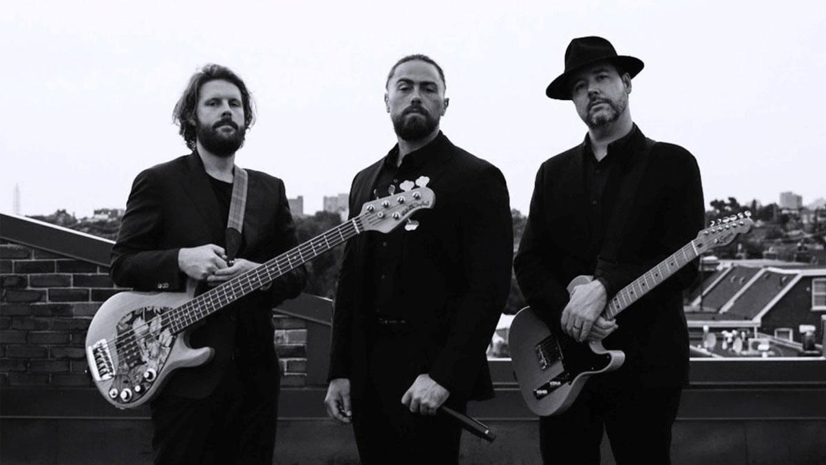 Two people holding guitar and one person in the middle holding a microphone