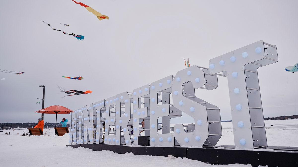 Winterfest sign with kites in the sky behind it