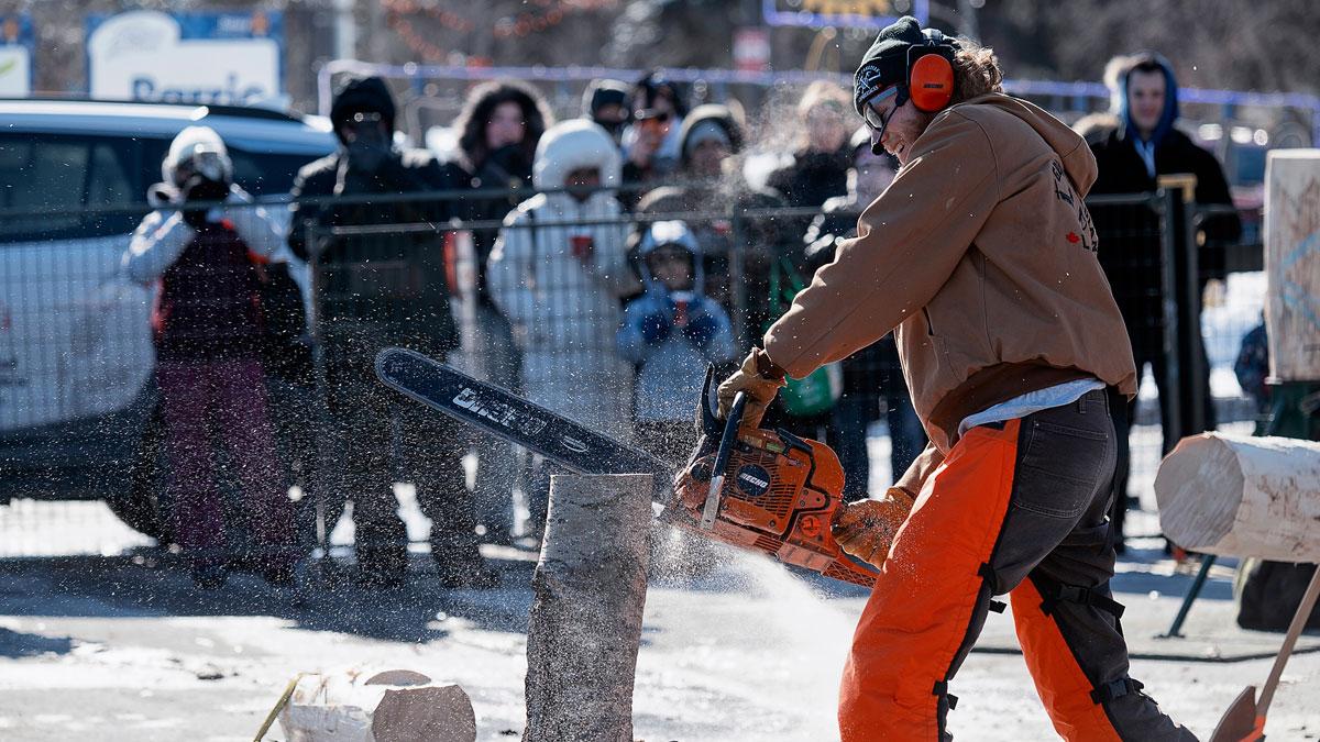 Lumberjacks sawing wood as the crowd watches