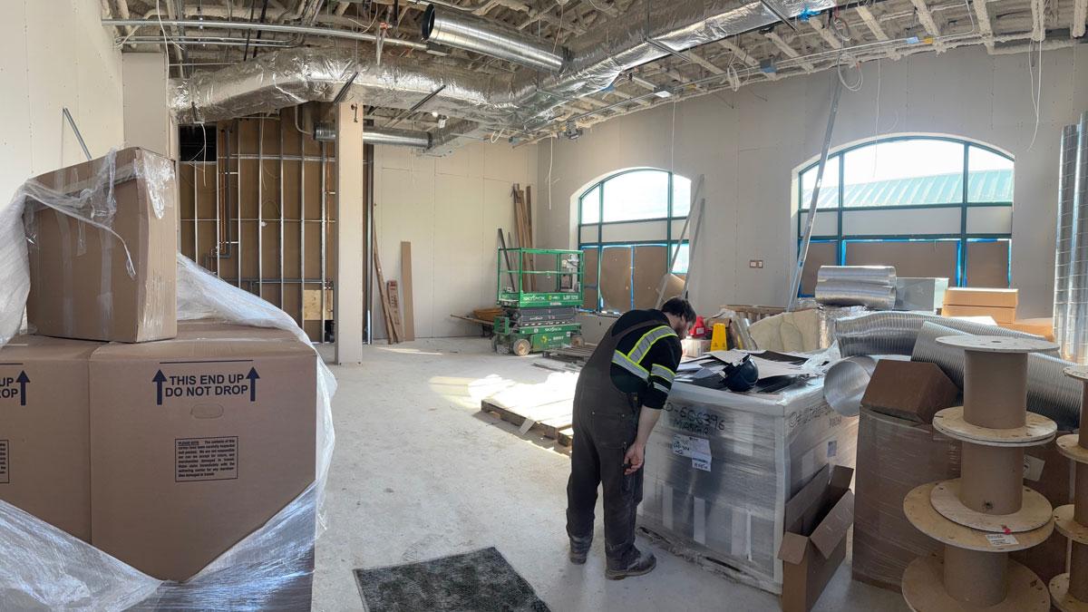 Inside of a building under construction with new drywall installed and a construction worker looking at documents.