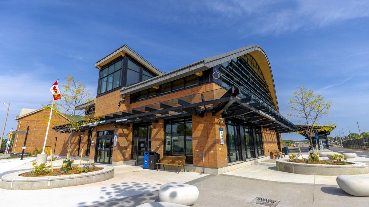 Modern brick building with a Canadian flag and landscaped plaza.
