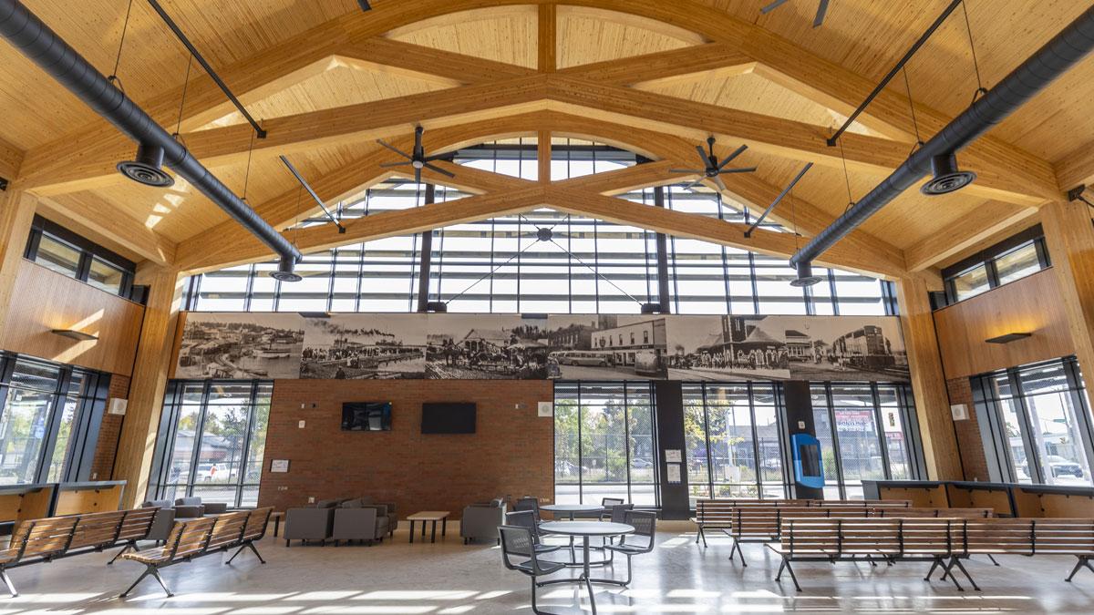 Spacious room with wooden beams, wall art, large windows, chairs, and tables.