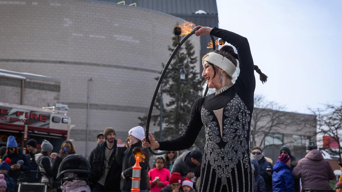 Fire performer with crowd in outdoor winter setting.