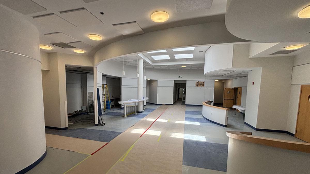 Modern interior space with curved walls, bright lighting, and blue and gray flooring.