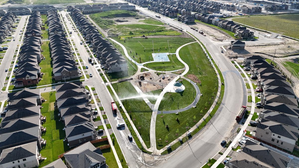 Aerial view of suburban neighborhood with curved roads and a park in the center.