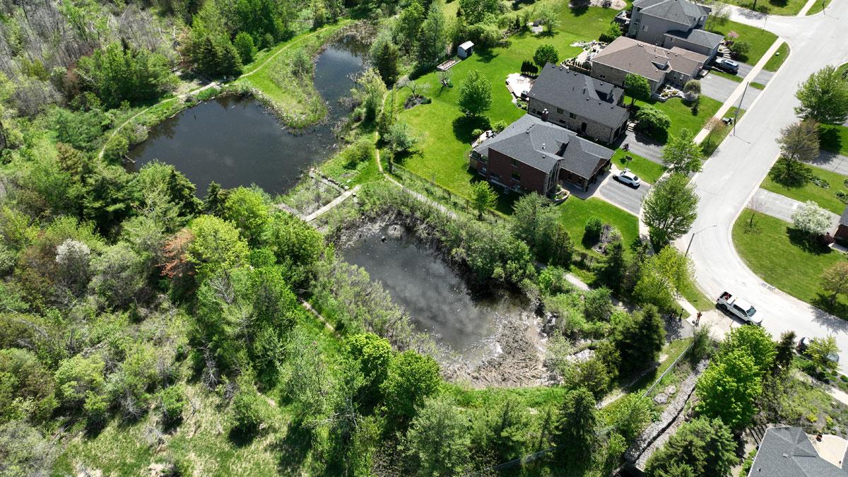 Aerial view of residential area with houses, green lawns, and two ponds.