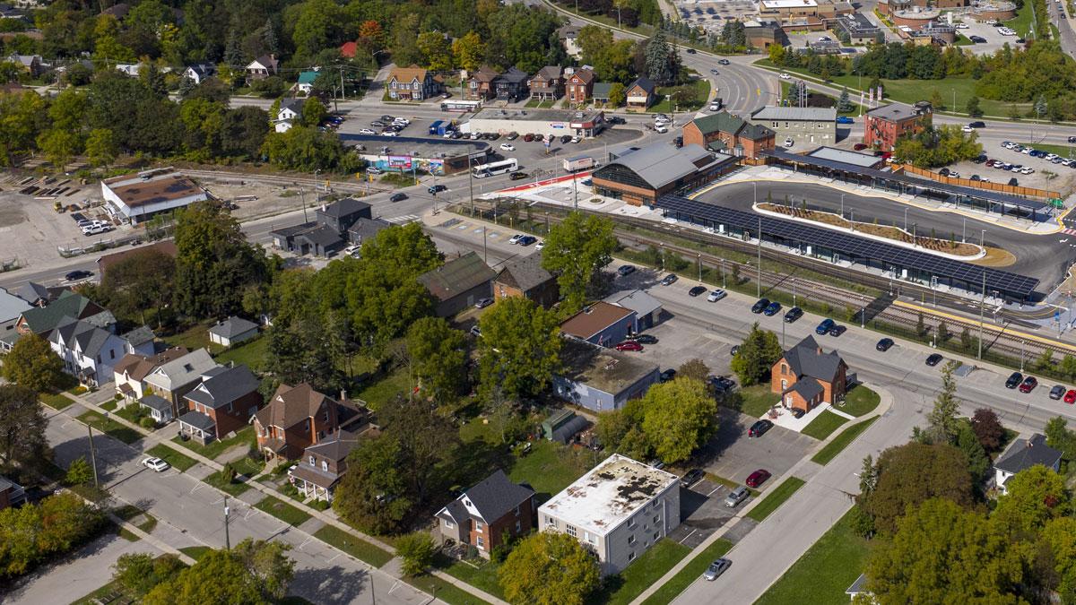 Aerial view of a neighbourhood with houses, trees and nearby commercial buildings.