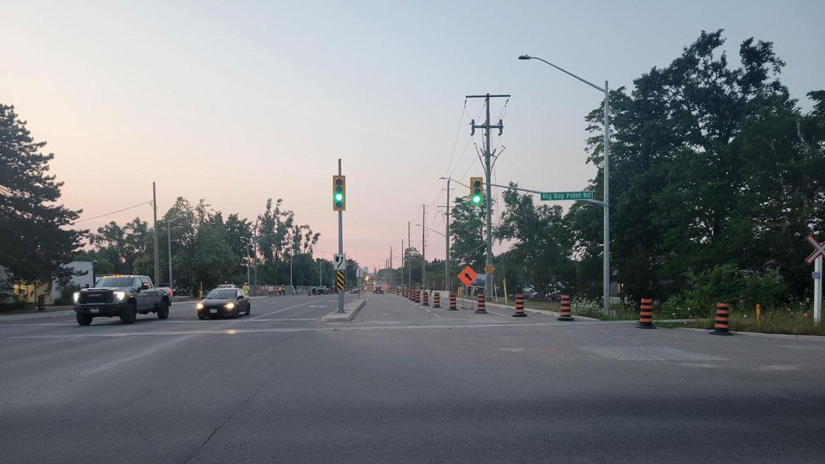 Traffic lights showing green at a wide road intersection during dusk.