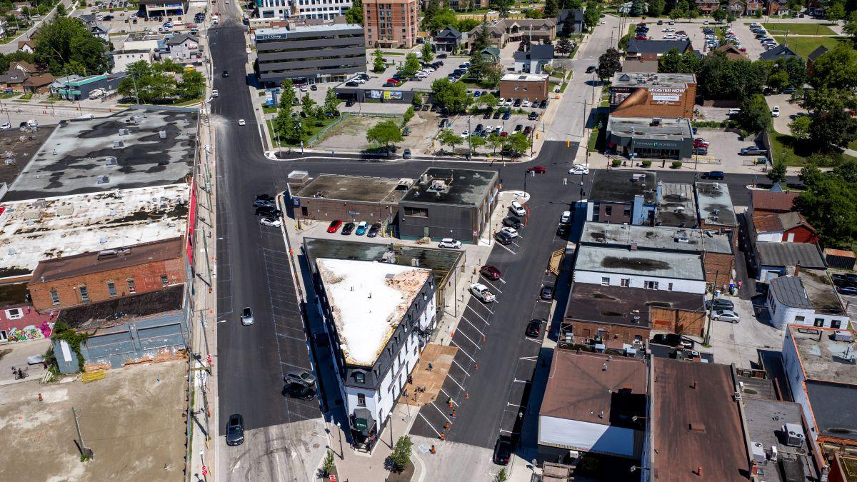 Aerial view of a triangular building surrounded by urban streets that are freshly paved and nearby buildings.