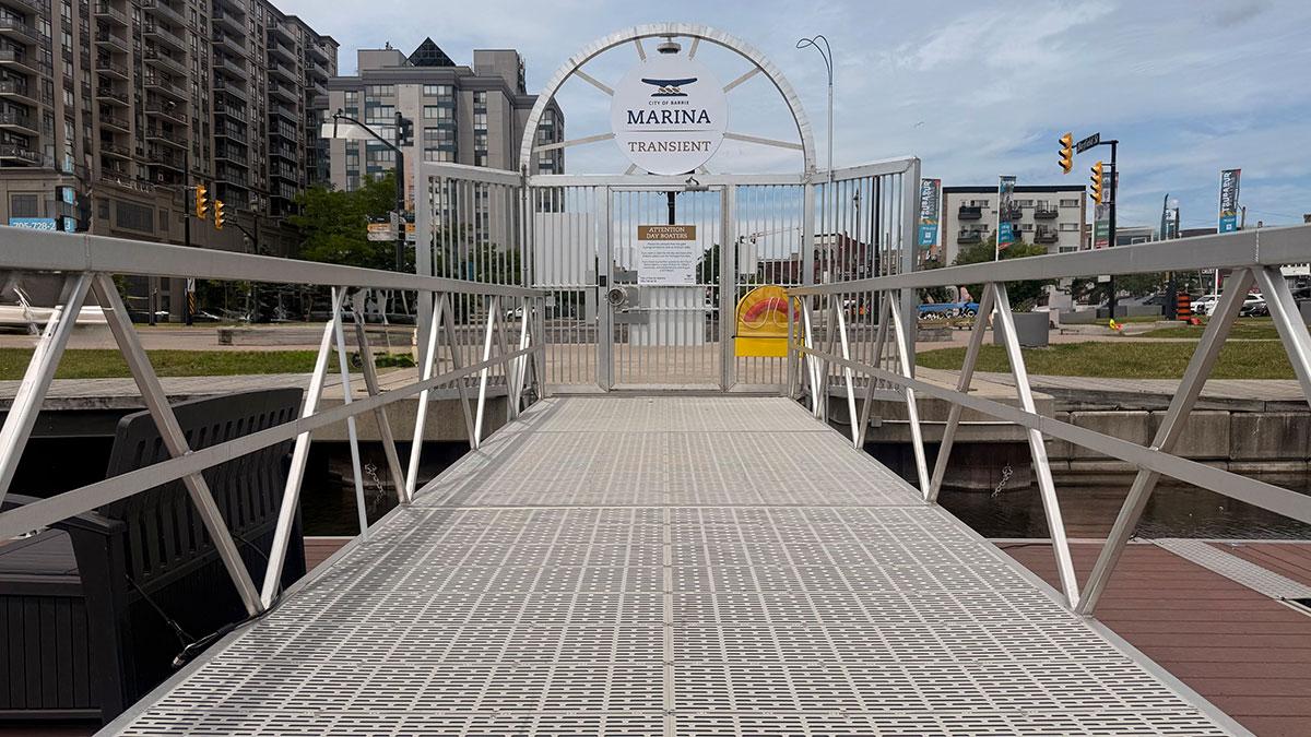 A metal dock leads to a gate with buildings in the background.