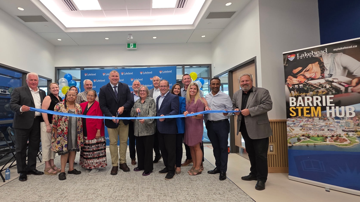 Group of people holding a ribbon for a ceremony at the Barrie STEM Hub.