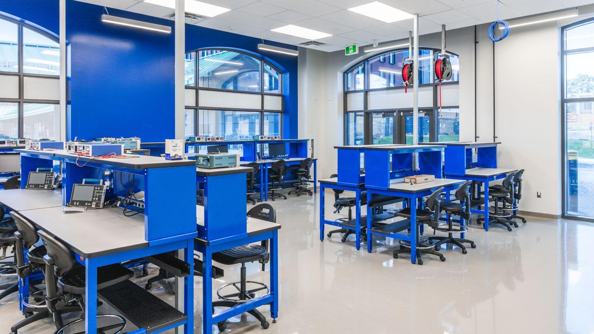 Bright classroom with blue walls and tables, featuring large windows and modern design.