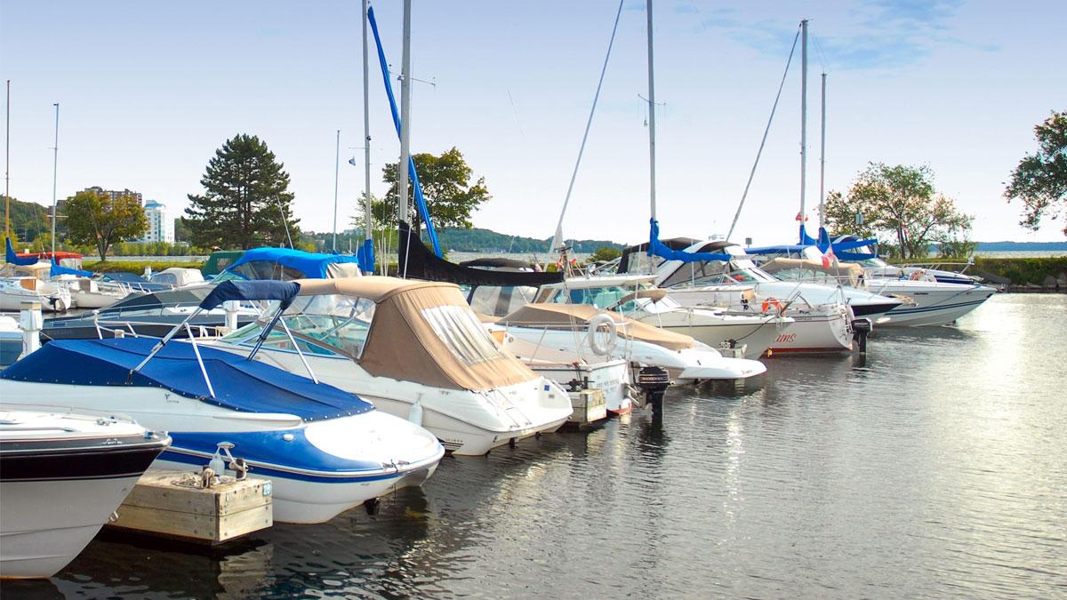 Marina scene with various boats docked, reflecting on calm water.