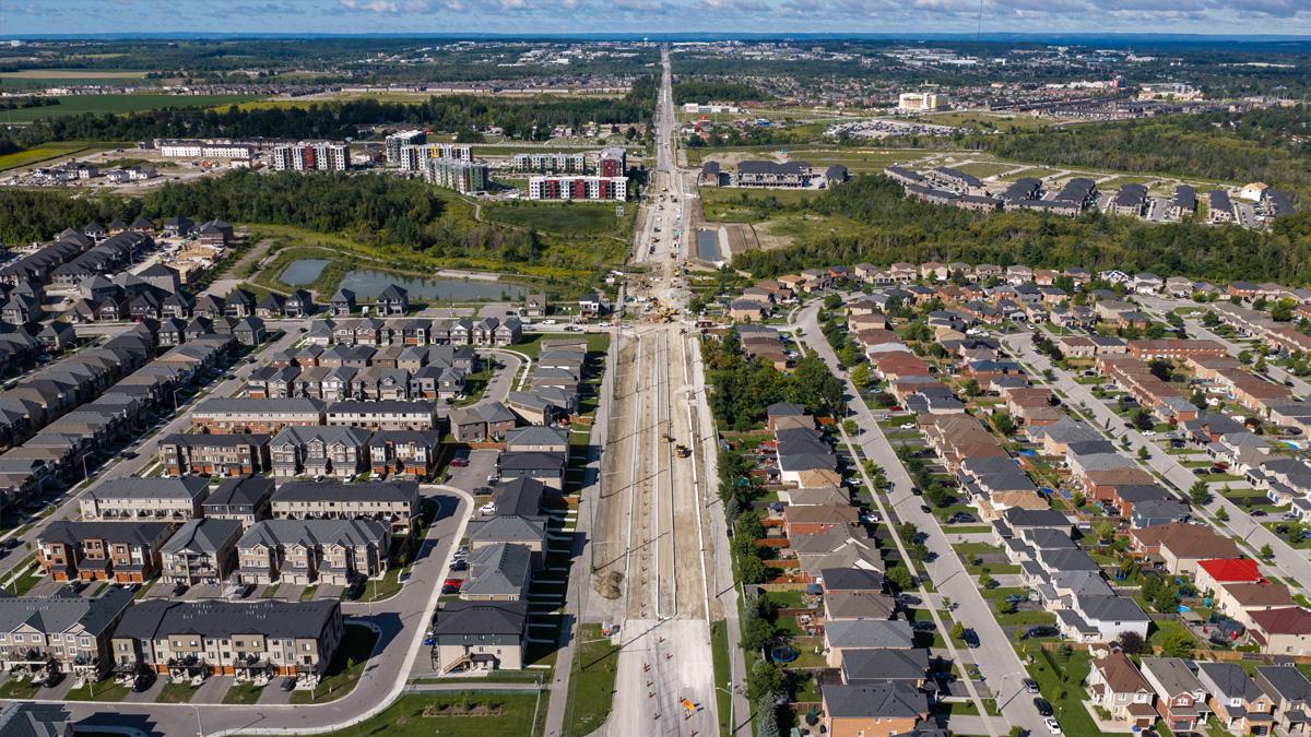 Aerial view of a suburban neighborhood with new construction along a wide road.