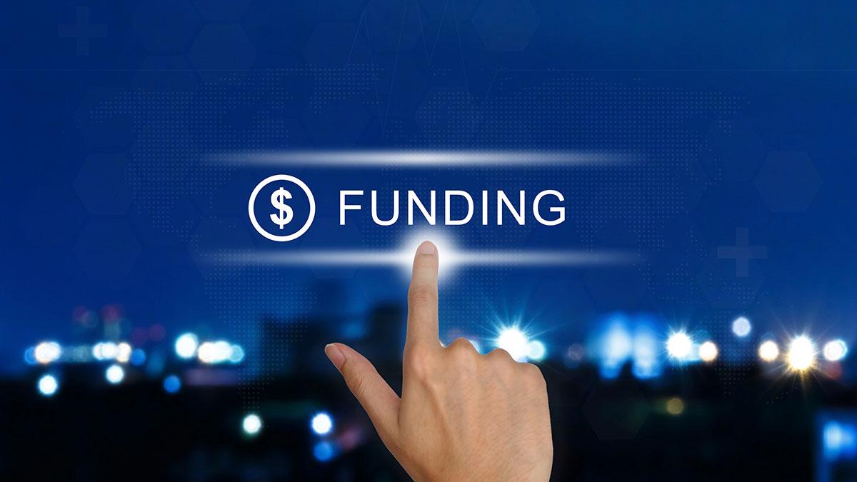 Text: Funding | Image: Hand with finger pushing button on cityscape