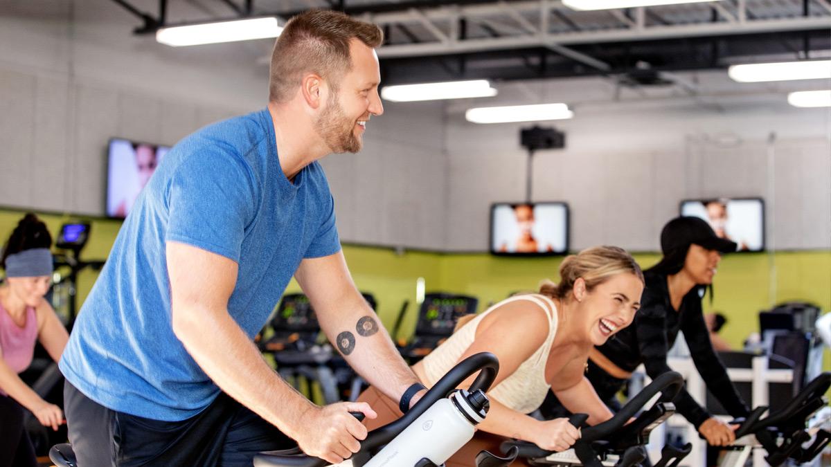 Happy people using stationary bikes