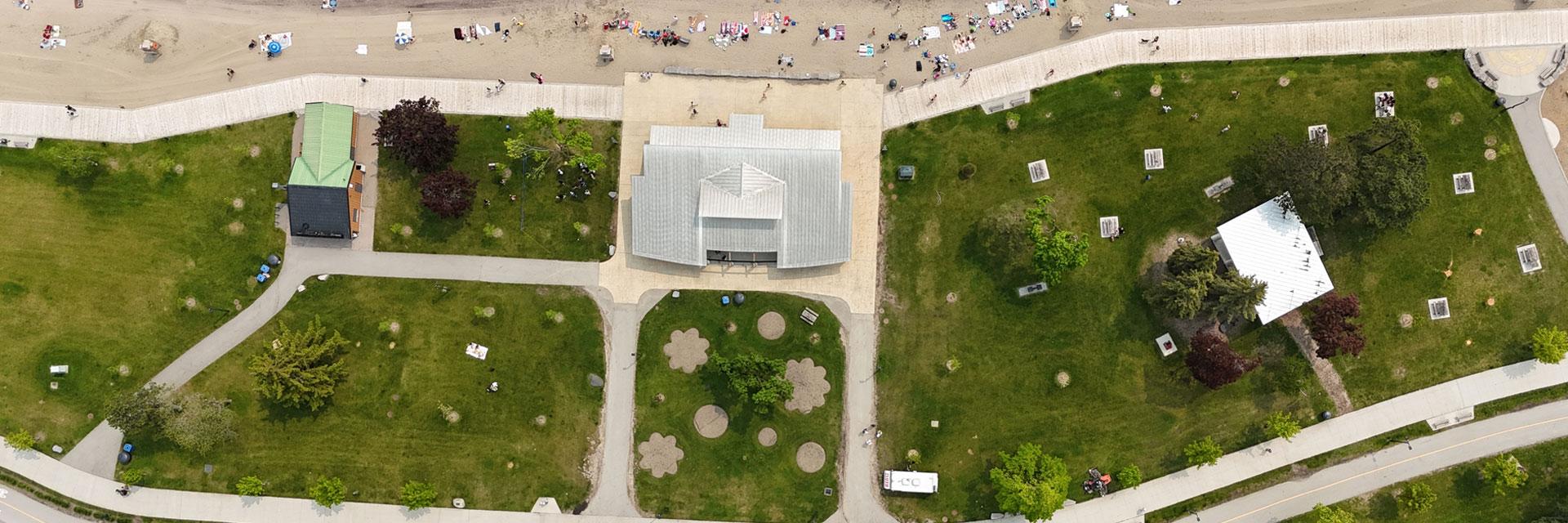 Aerial view of a park with green spaces, pathways, and a building in the center.
