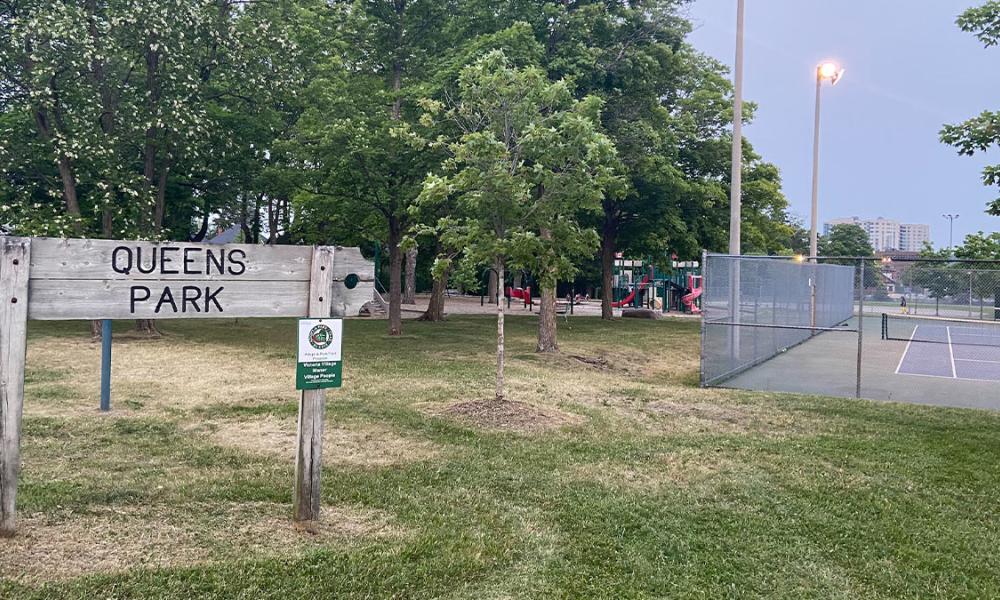 Queen's Park sign with tennis courts and playground in background