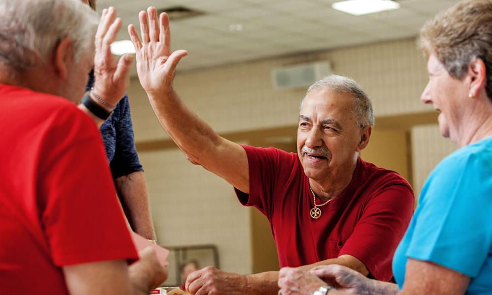 Seniors playing cards and high-fiving