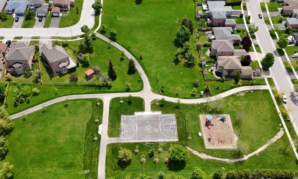 aerial view of playground and sports court, surrounded by grass and nearby houses