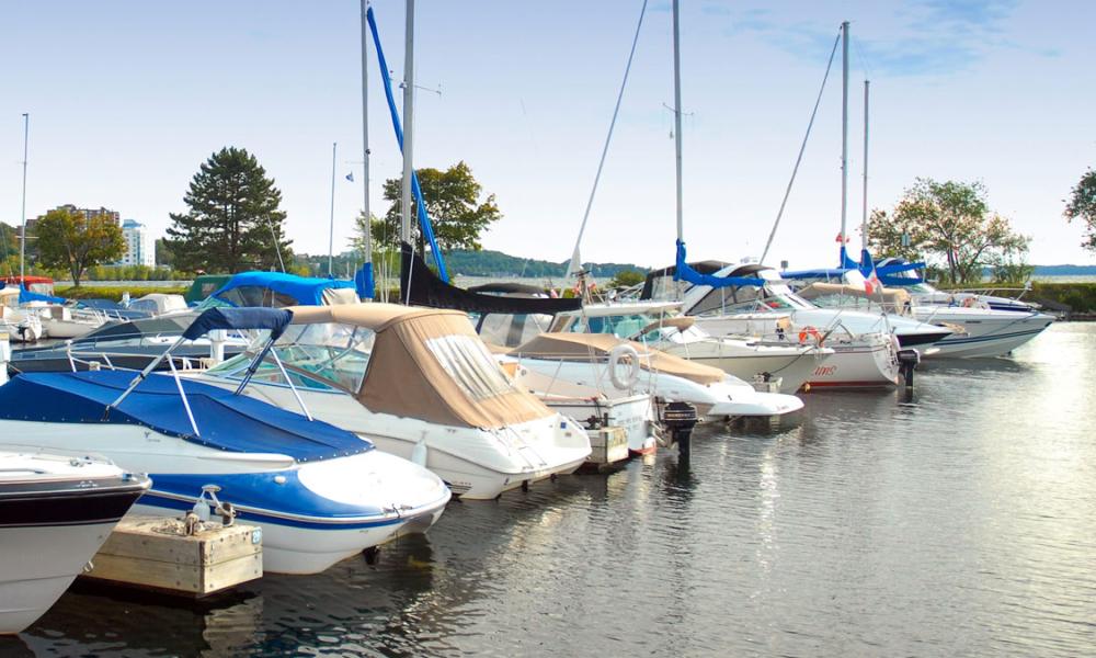 Marina scene with various boats docked, reflecting on calm water.