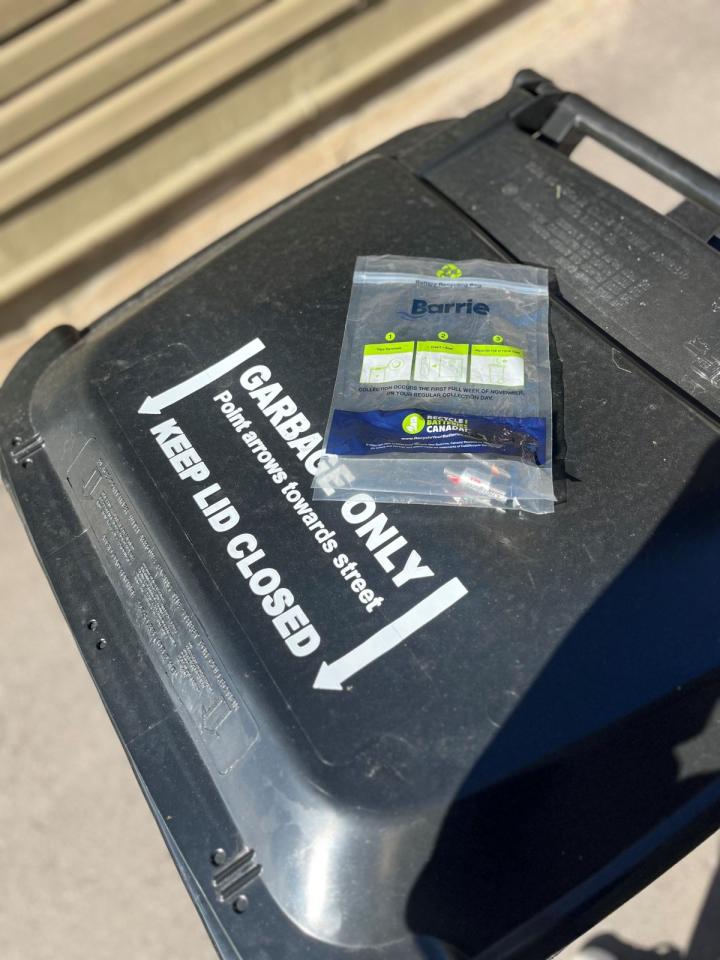 Filled battery recycling bag on top of City of Barrie garbage cart