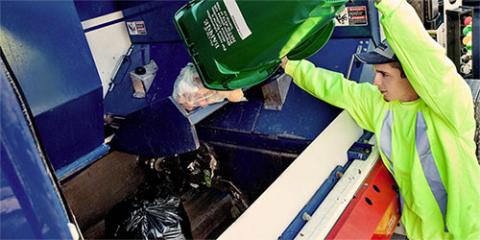 Man dumping organics bin into waste collection truck